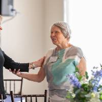 Donna Brooks smiling, chatting with Claudia Bajema and putting a friendly hand on her sholder